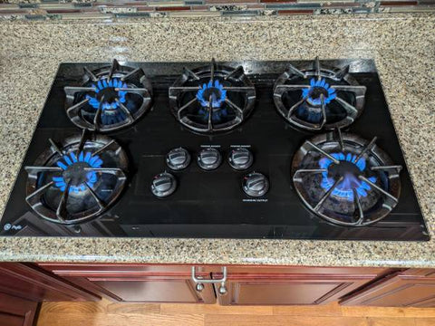 Image of installed 36", 5 gas burner, G.E. cooktop with burners aflame. 