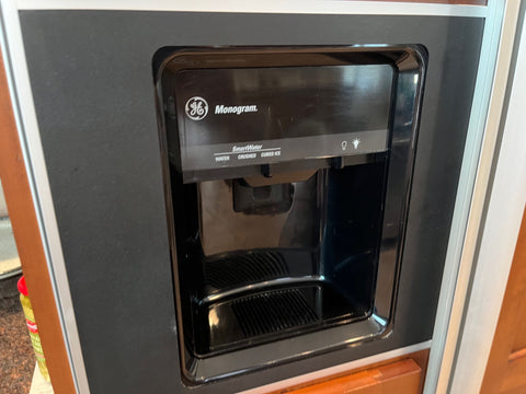 Close-up view of G.E. Monogram refrigerator in-door water and ice dispenser with light. 