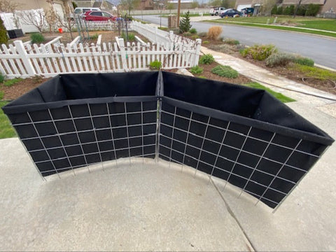 Two raised bed planter boxes, unfolded, with black liners installed. 