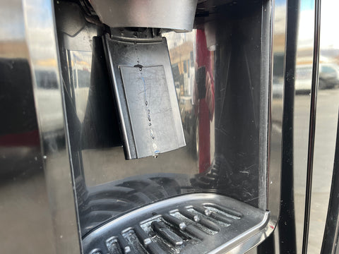 Detail of water & ice dispenser on the outside of a GE DSE24JGHBCBB refrigerator. 