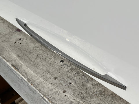 Detail of chrome, arced handle on gloss white face of IKEA horizontal cabinet. 