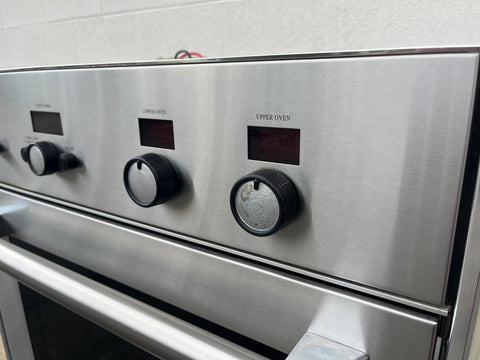Thermador stainless steel double oven control panels with knobs and digital displays. 