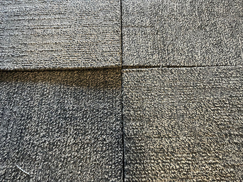 Detail of good, used, 20", 3/8" thick, commercial carpet tiles in a tan & black pattern. 