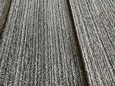 Close up of good, used, 10x39.5 inch, 3/8" thick, commercial carpet tile in lined dark gray. 