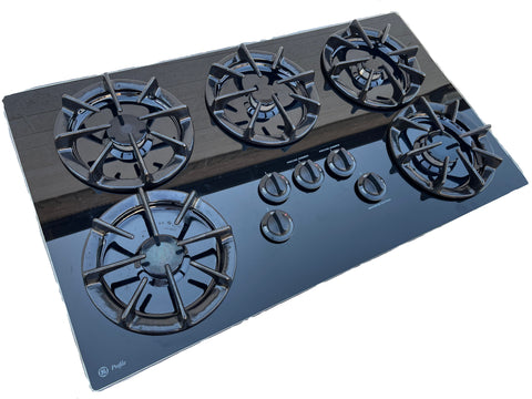 3/4 left view of good used GE Profile 36" gas cooktop with removable cast iron grates. 