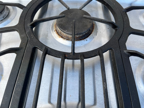 Detail of center burner of Jenn-Air 36" gas cooktop featuring continuous cast iron grates. 