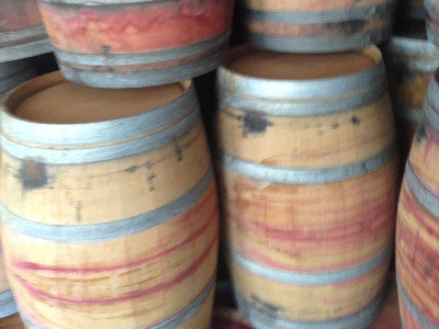 Picture of stacked reclaimed wine barrels. Material Resourcers repurposes materials from industrial & manufacturing companies. Bring us your waste, excess, non-recyclable, by-product, remnant, blemished, cancelled, and expired materials.